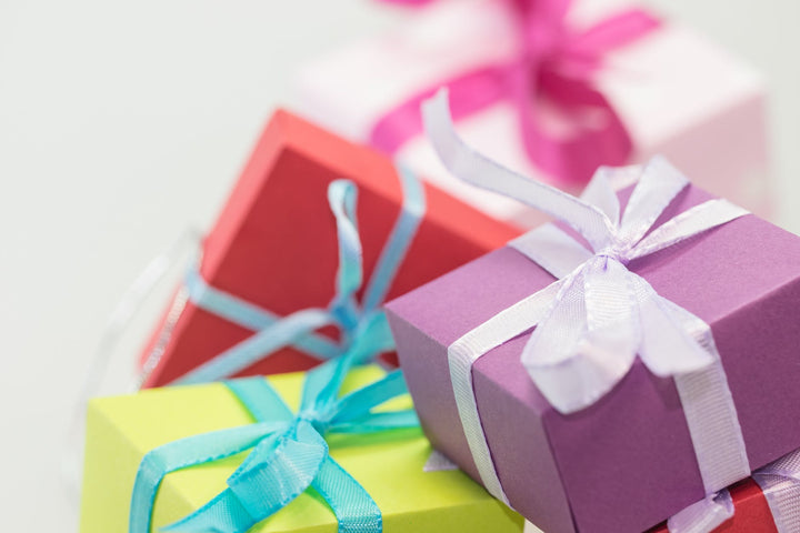 selective focus photography of gift boxes|children behind a boy sitting on a couch holding gift boxes