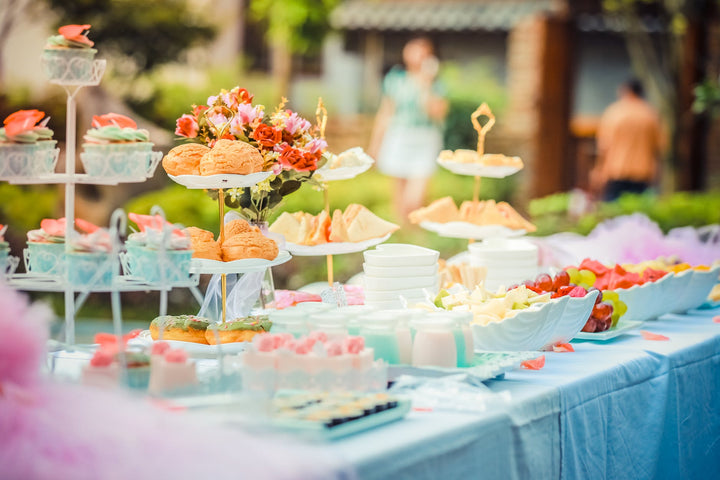 various desserts on a table covered with baby blue cover|pregnant woman showing off baby shower gifts with friends