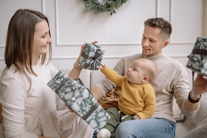 a family with christmas presents|a father kissing his baby on the cheek