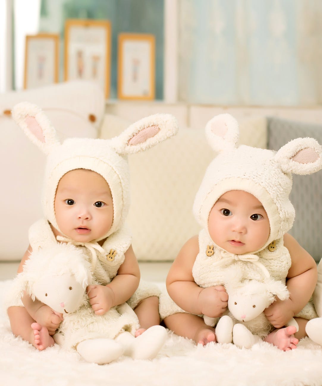 baby-twins-brother-and-sister-one-hundred-days.jpg|baby lying on white cushion beside brown bear plush toy