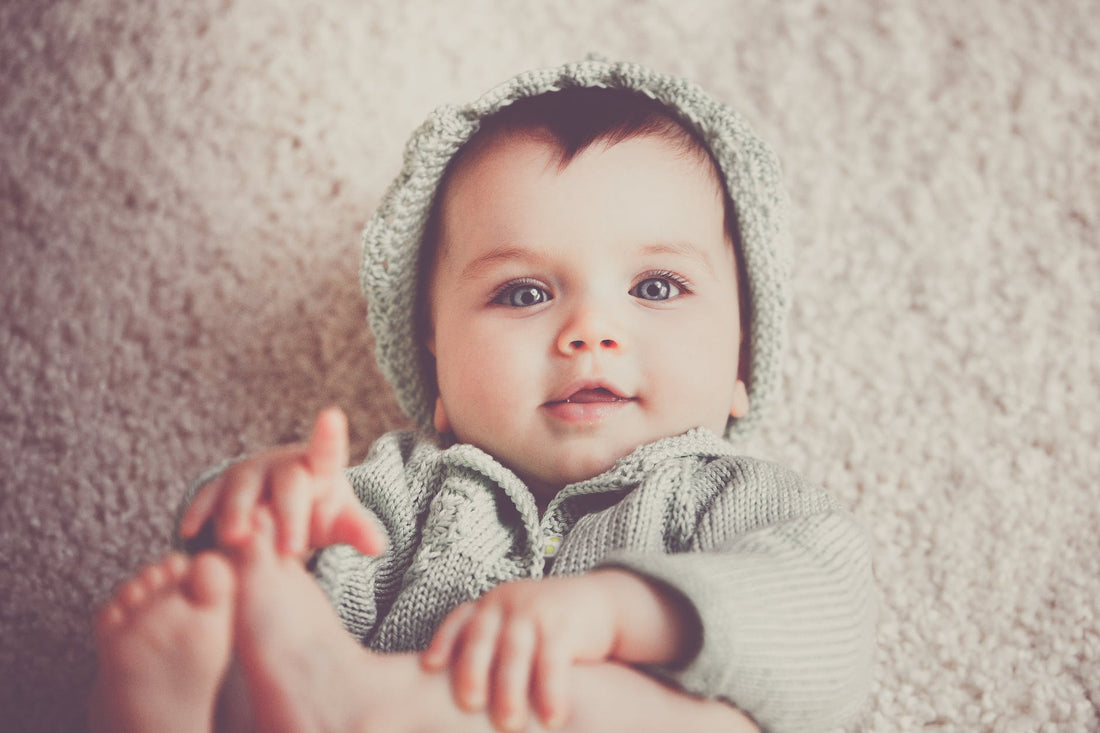 baby on gray knit hooded clothes lying on carpet|innocent little child with nipple sleeping in bed