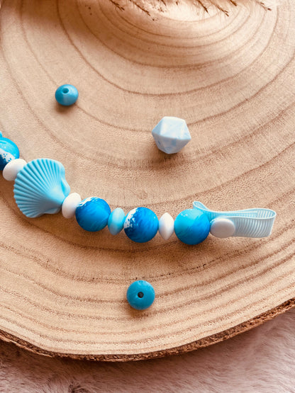 Détail du clip en bois de hêtre de l'attache tétine personnalisée coquillage bleu