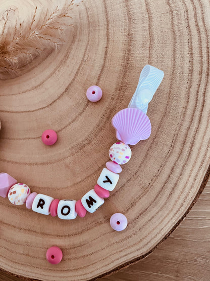 Détail du pendentif coquillage et du clip en bois de hêtre de l'attache tétine personnalisée rose