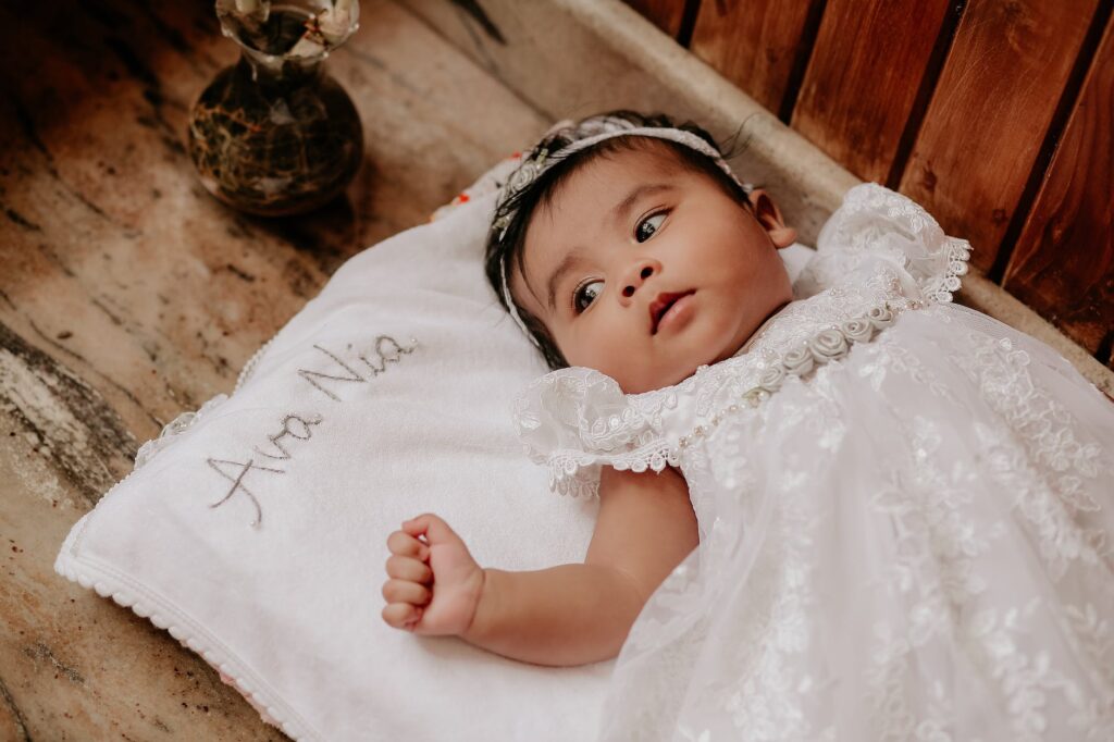 baby in white dress lying down on blanket with name